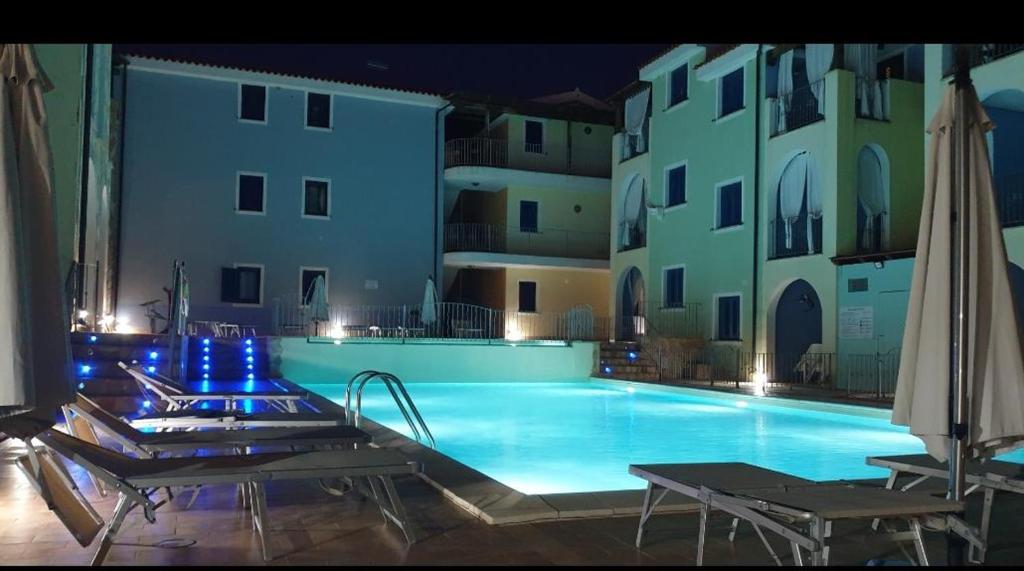 una grande piscina con due sedie e un edificio di Sea Paradise Apartment a Valledoria