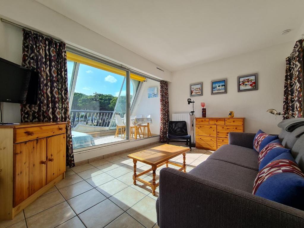 un salon avec un canapé et une télévision dans l'établissement Studio 261 escale plage résidence, au Grau-du-Roi