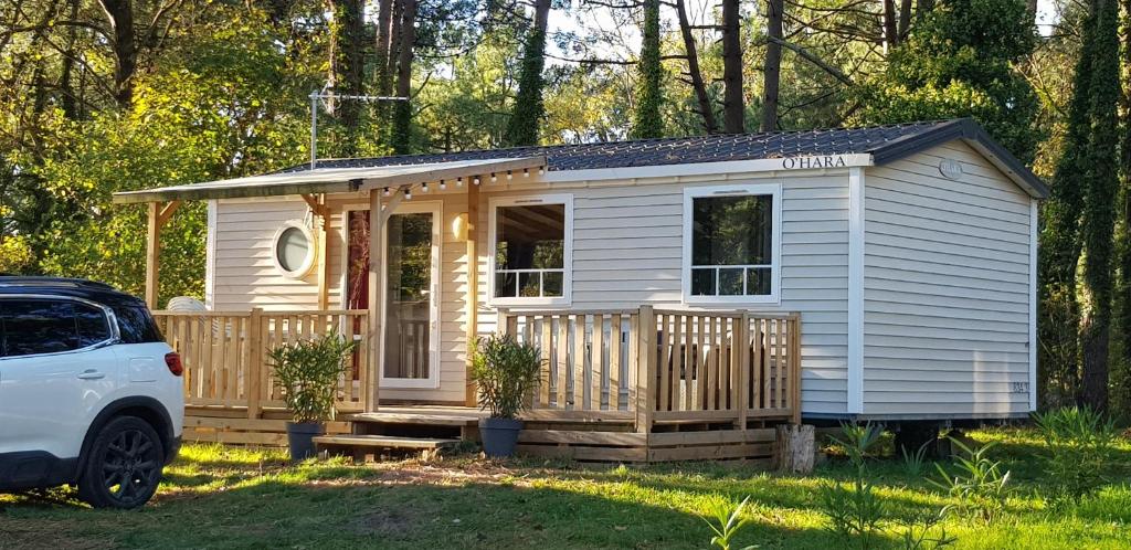 a small white tiny house with a porch at LE ILÔ - camping la dune blanche in Camiers