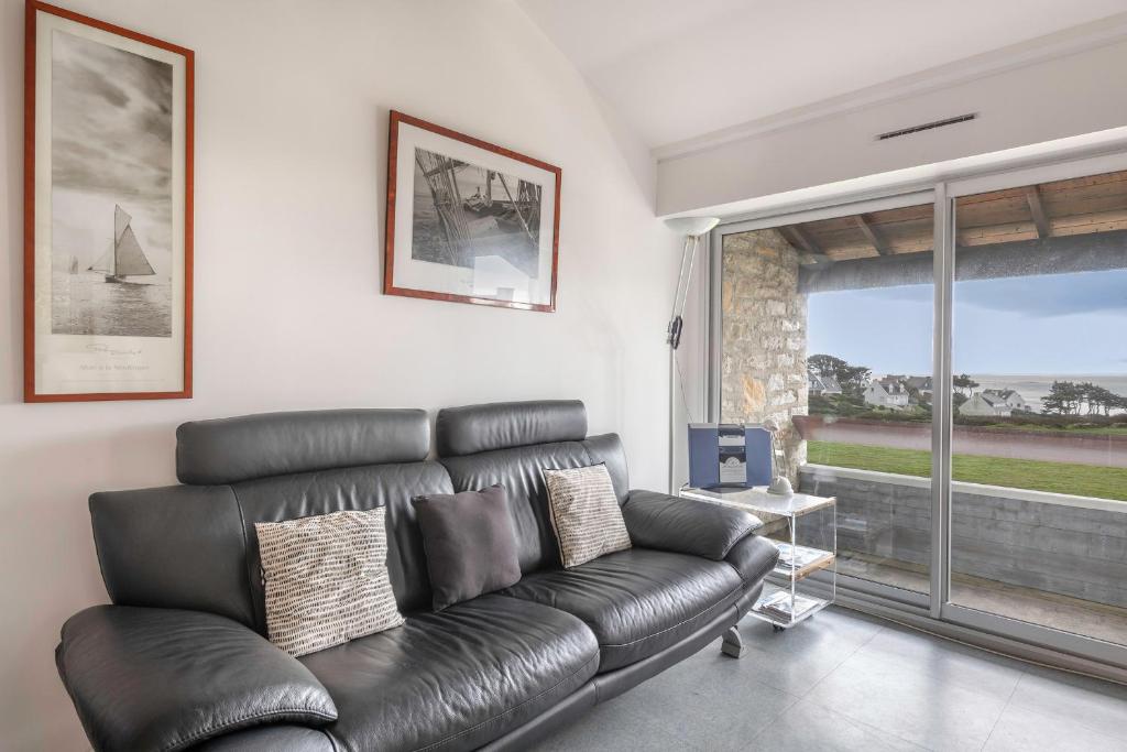czarna skórzana kanapa w salonie z oknem w obiekcie Appartement accueillant pour 4 personnes, a quelques metres de la plage w mieście Saint-Gildas-de-Rhuys