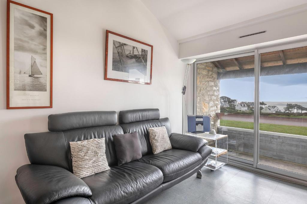 ein schwarzes Ledersofa im Wohnzimmer mit Fenster in der Unterkunft À 300m des plages, 2 adultes - 2 enfants in Saint-Gildas-de-Rhuys