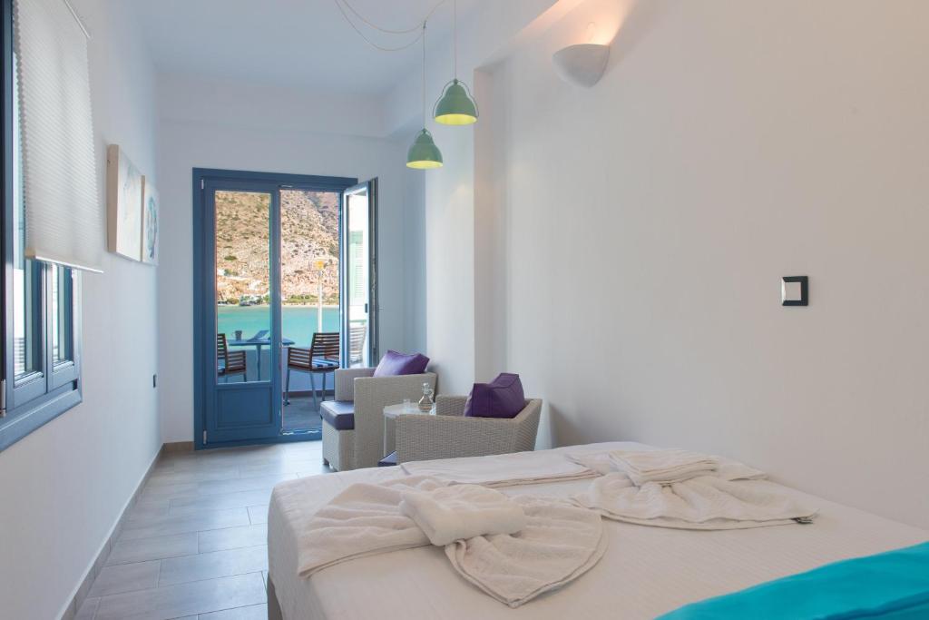a white bedroom with a bed and a patio at BLUE Seaside Studio in Sifnos