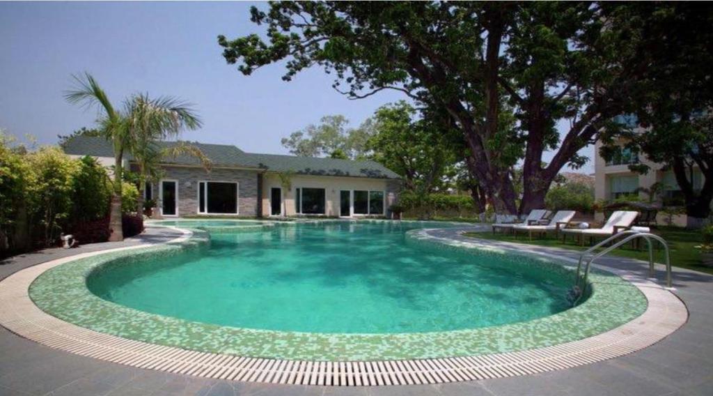 een groot zwembad in een tuin met een huis bij Godwin Haridwar in Haridwār