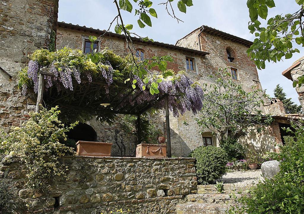 an old stone building with purple flowers on it at Corzano e Paterno in San Casciano in Val di Pesa