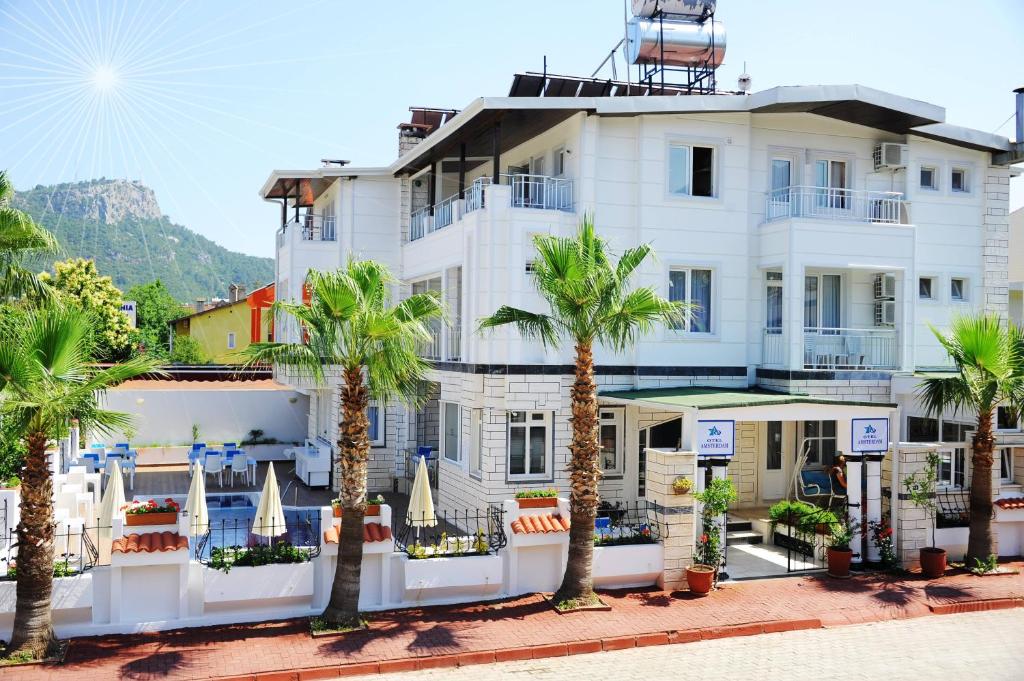 a large white building with palm trees in front of it at Amsterdam Otel & Suite Apart in Kemer