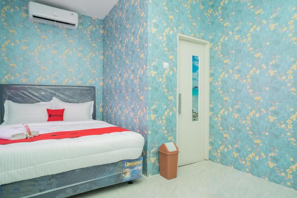 1 dormitorio con 1 cama y paredes azules con flores en RedDoorz Plus near ITC Cempaka Mas 2, en Yakarta