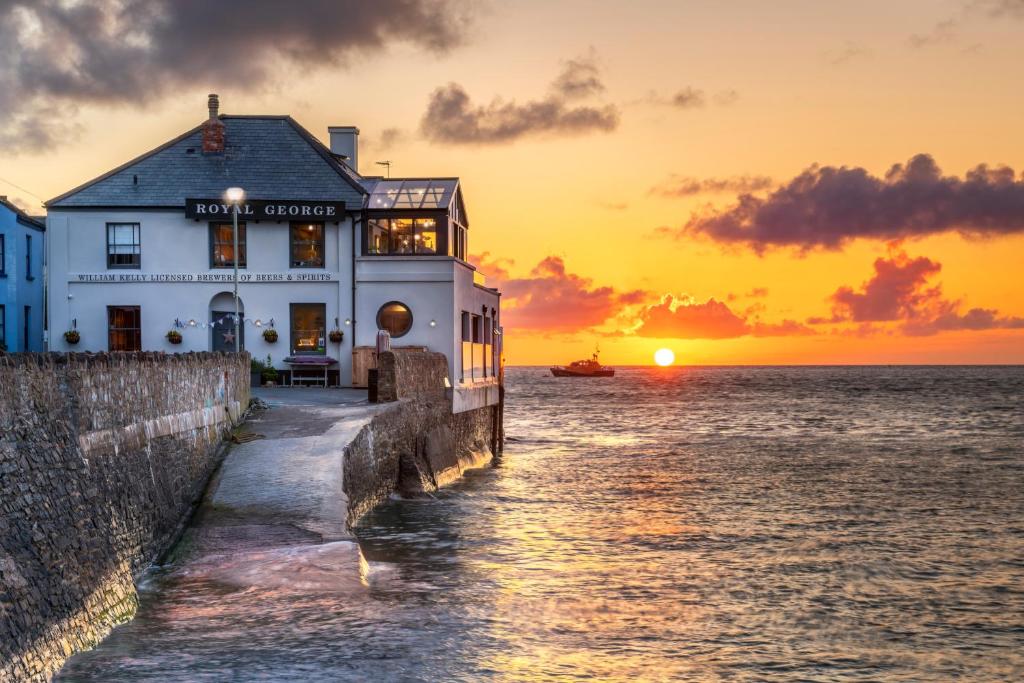 een gebouw op het water met de zonsondergang op de achtergrond bij The Royal George in Appledore