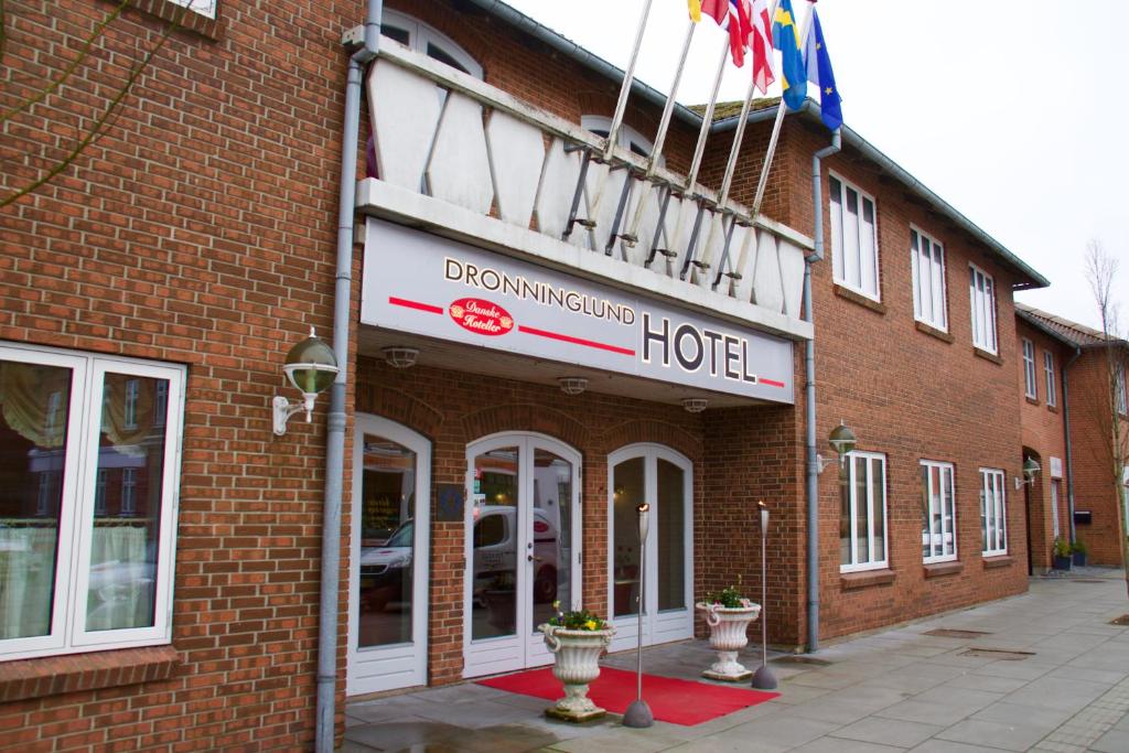 um edifício de tijolos vermelhos com uma placa de hotel em Dronninglund Hotel em Dronninglund