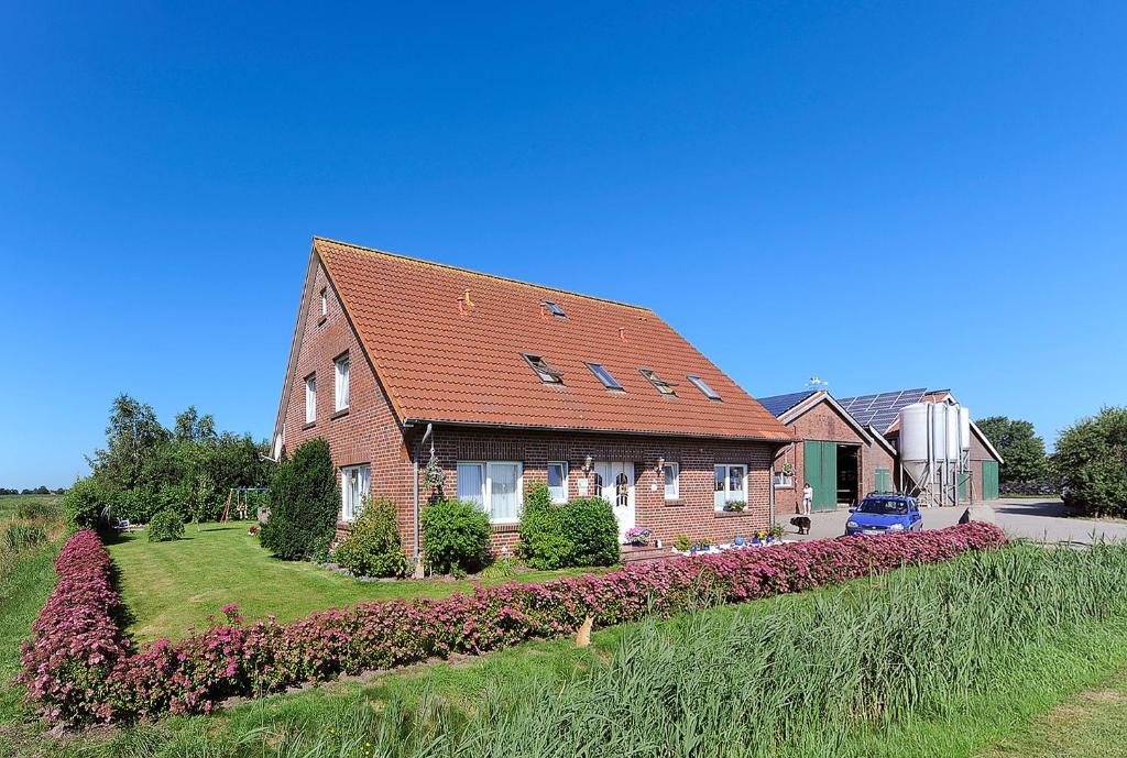 a brick house with a landscaping in front of it at Ferienwohnungen auf dem Ferienhof Elke Peters in Holtgast