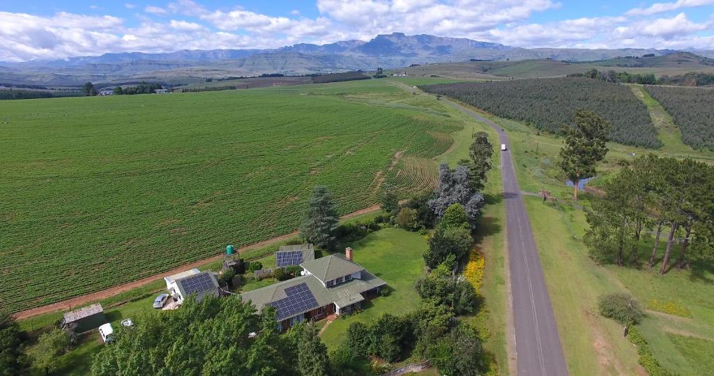 una casa en medio de un campo con una carretera en Little Acres Drakensberg Accommodation, en Champagne Valley