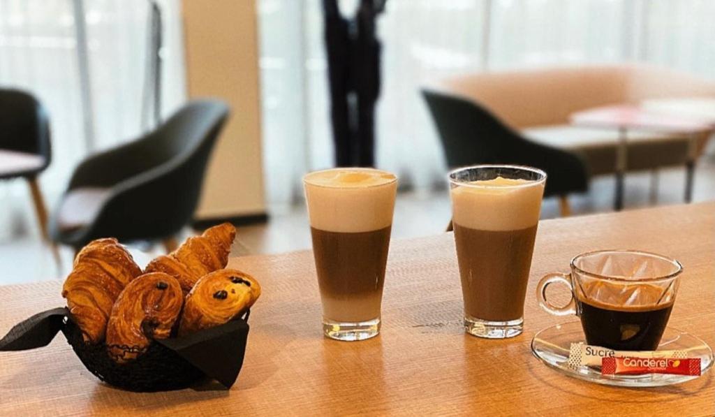 a table with two glasses of beer and a basket of pastries at Holiday Inn Express - Paris - CDG Airport by IHG in Roissy-en-France