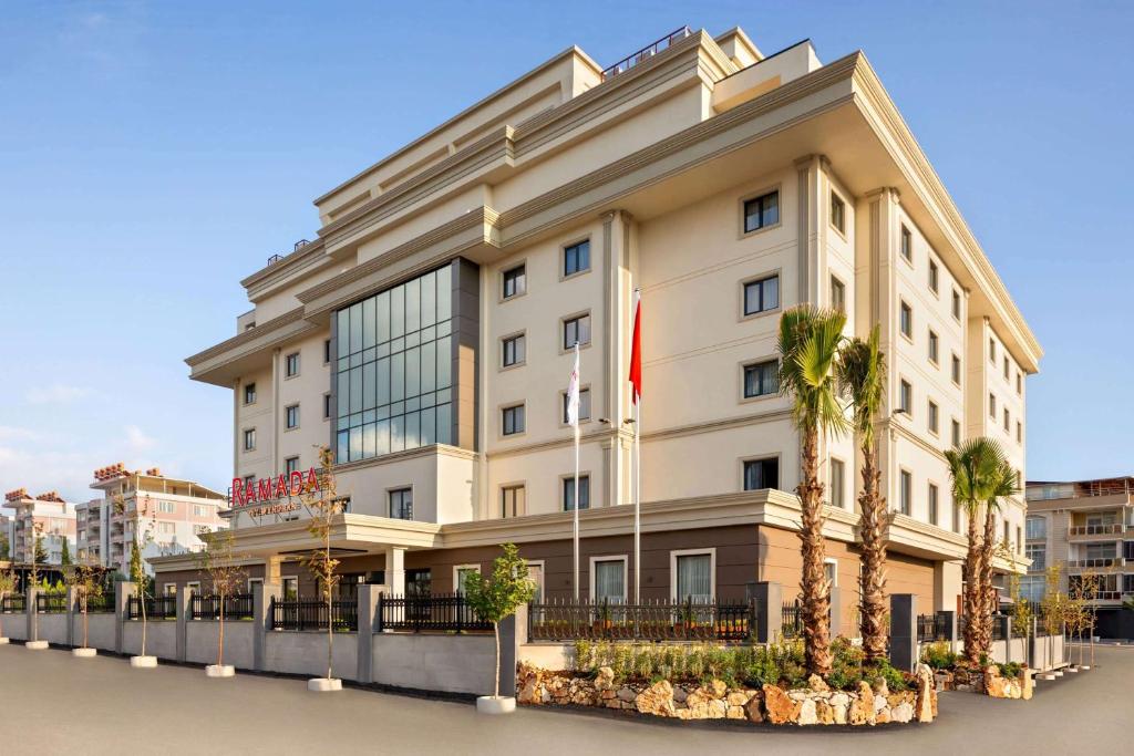 een groot wit gebouw met palmbomen ervoor bij Ramada by Wyndham Adiyaman in Adıyaman