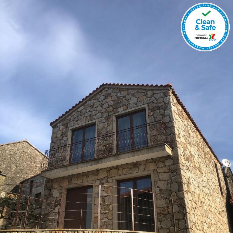 a stone house with a balcony and a sign that says clean and safe at Casa do Palheiro in Pitões das Júnias