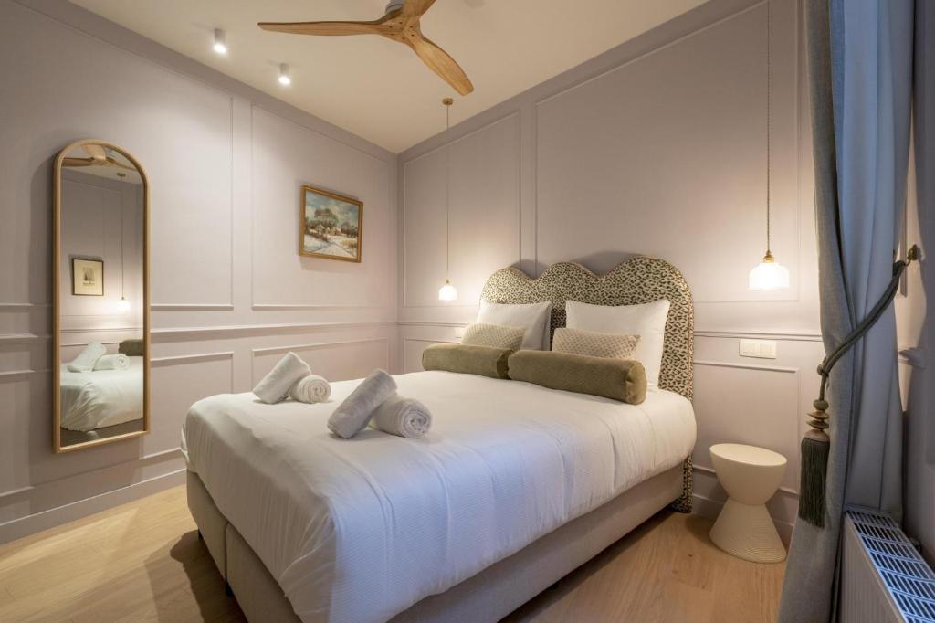 1 dormitorio con 1 cama blanca grande y espejo en Le Marnix, en Amberes