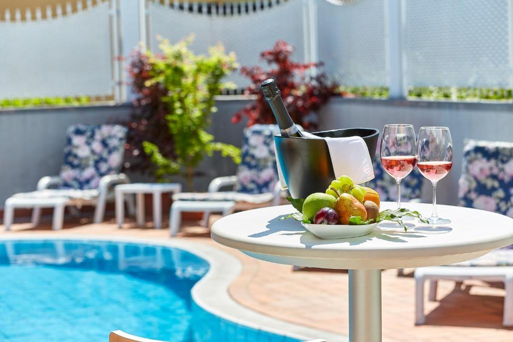 una mesa con copas de vino y fruta junto a una piscina en Villa Azzurra Depandance con piscina, en Desenzano del Garda