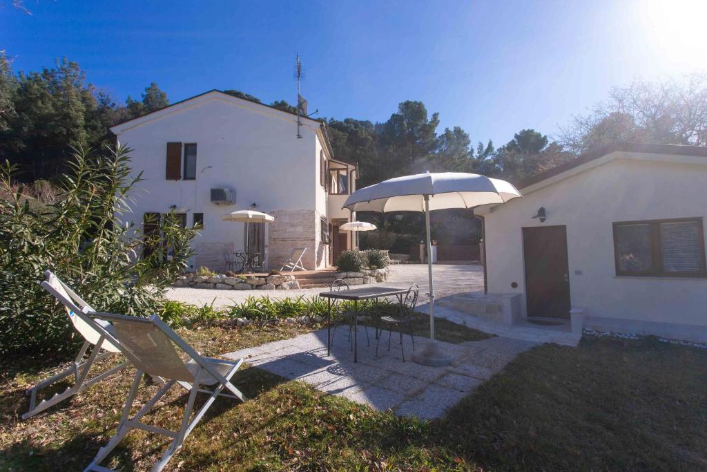 a pair of chairs and an umbrella in front of a house at A06 - Massignano, meravigliosa camera con vista in Massignano