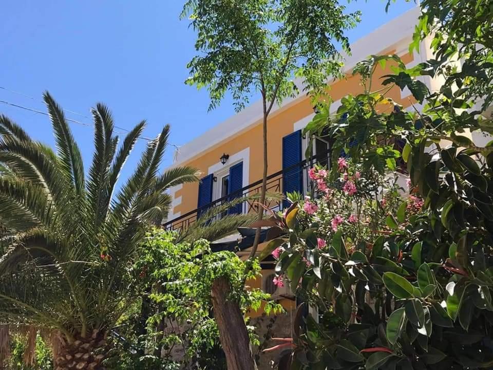 un edificio amarillo con puertas azules y palmeras en Plumeria Flowery, en Agios Kirykos