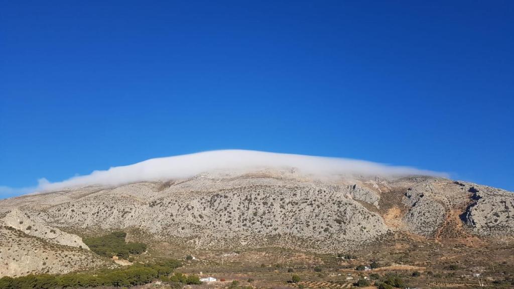 una montaña con una nube cubriendo la parte superior de ella en Cortijo Don Camilo de La HUMA en El Chorro