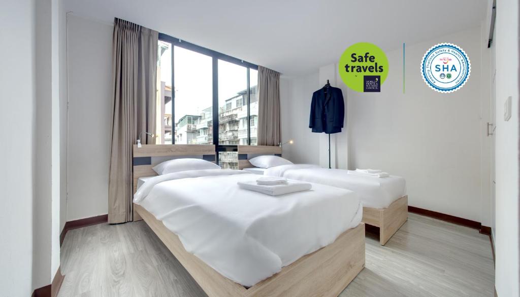 two beds in a room with a sign that reads she travels at Le Bonheur Poshtel in Bangkok