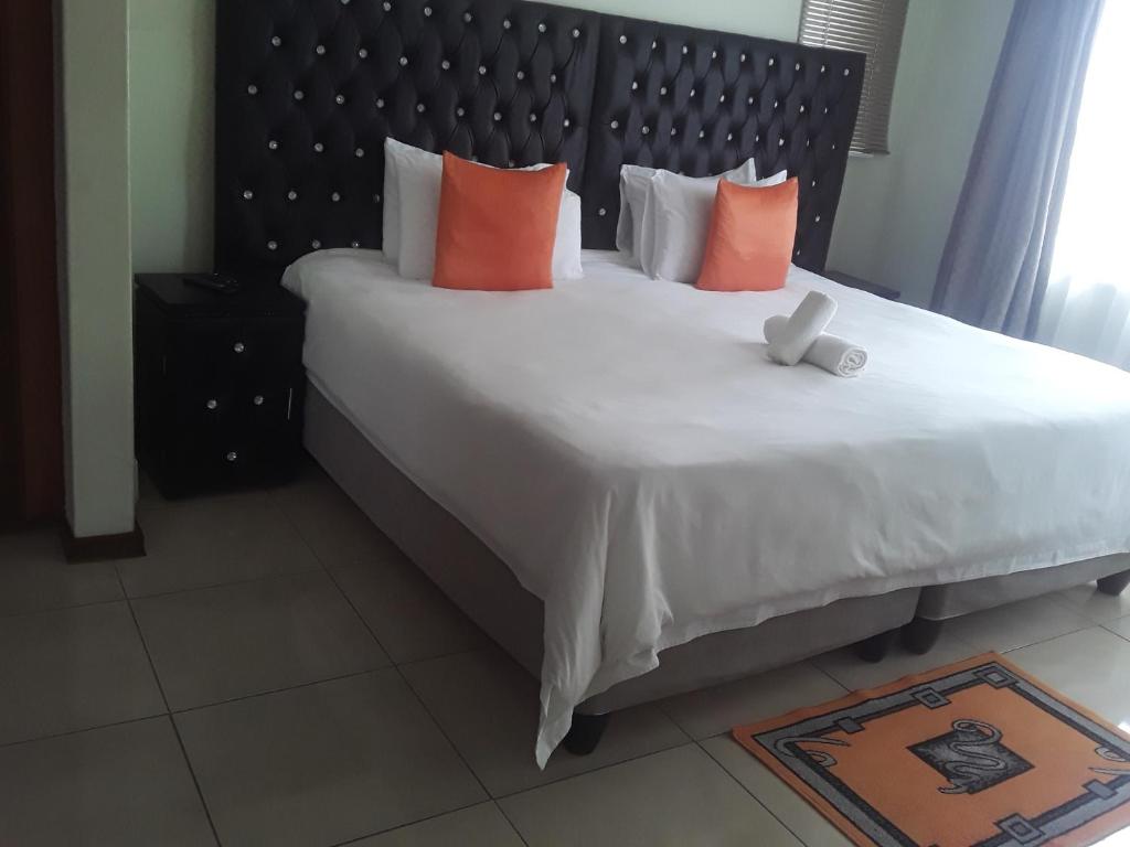 um quarto com uma cama grande e almofadas laranja em Kuyasa guesthouse em Mthatha