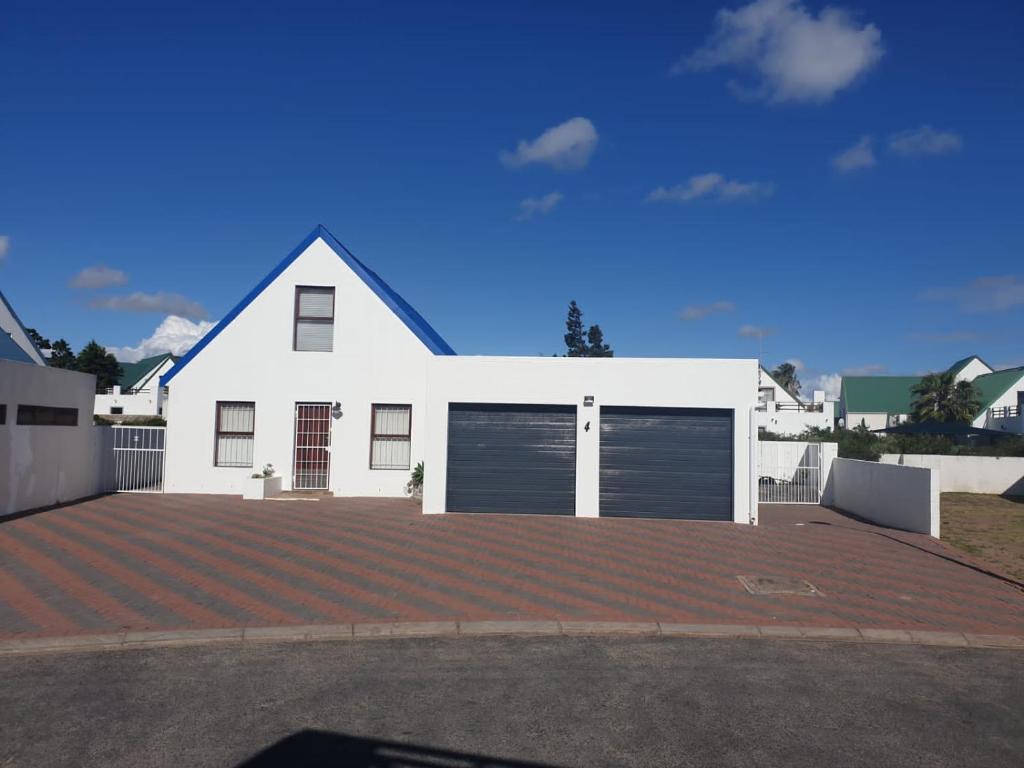 a white house with a garage and a driveway at 5 bedroom home in Langebaan, located close to Club Mykanos and Laguna Mall in Langebaan