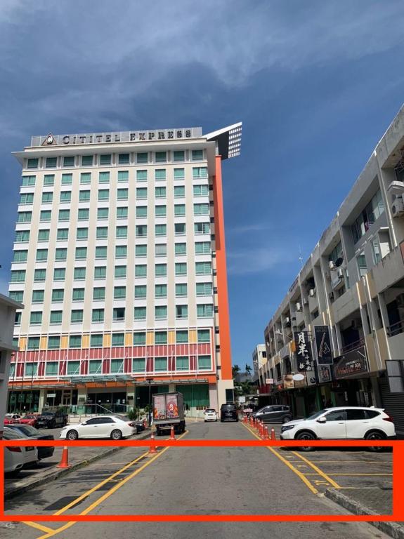 a large white building with cars parked in a parking lot at ACJ Residence @ Beside Cititel Hotel in Kota Kinabalu