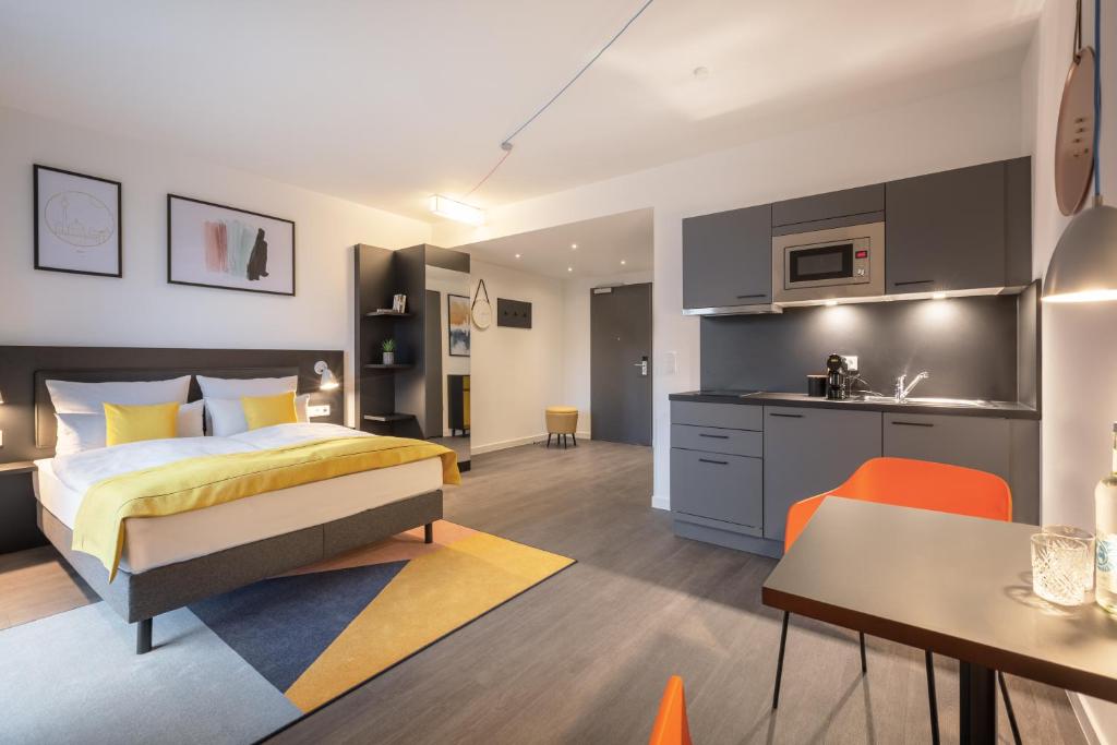 a bedroom with a king sized bed and a kitchen at acora Berlin Living the City in Berlin