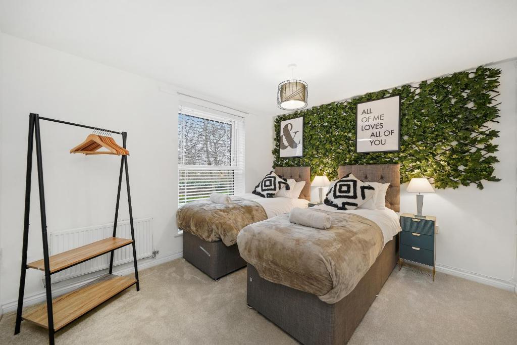 a bedroom with two beds and a ivy wall at Stylish 2 Bedroom 2 Bathroom Apartment - 8 Minutes Drive to Central MK - Free Parking, Fast WiFi & Smart TV by Yoko Property in Milton Keynes
