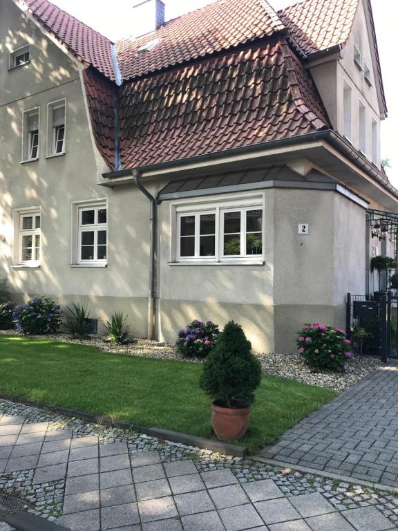 ein Haus mit einem Kacheldach und einem grünen Garten in der Unterkunft Haus in der Gartenstadt in Bottrop