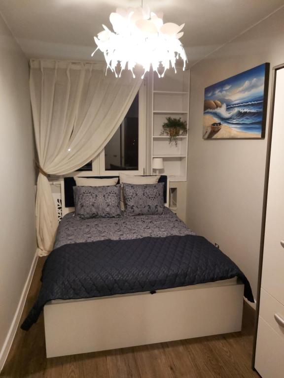 a bedroom with a bed and a chandelier at Apartament IZBA - mieszkanie na doby GDAŃSK in Gdańsk