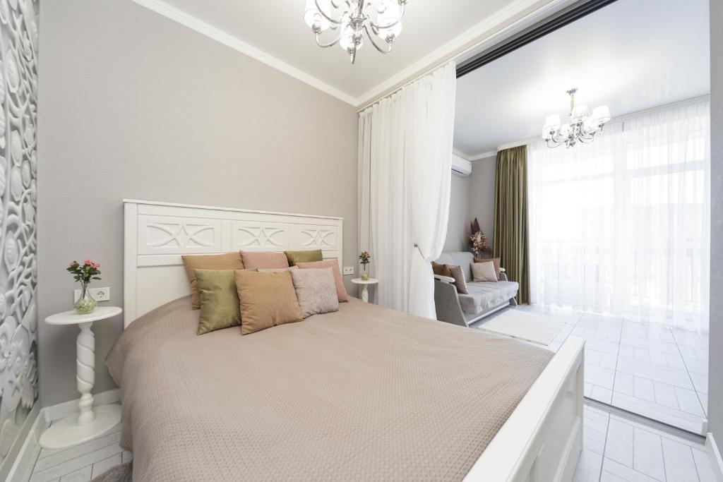 a white bedroom with a large bed and a chandelier at Apartments Park Fountains in Liski