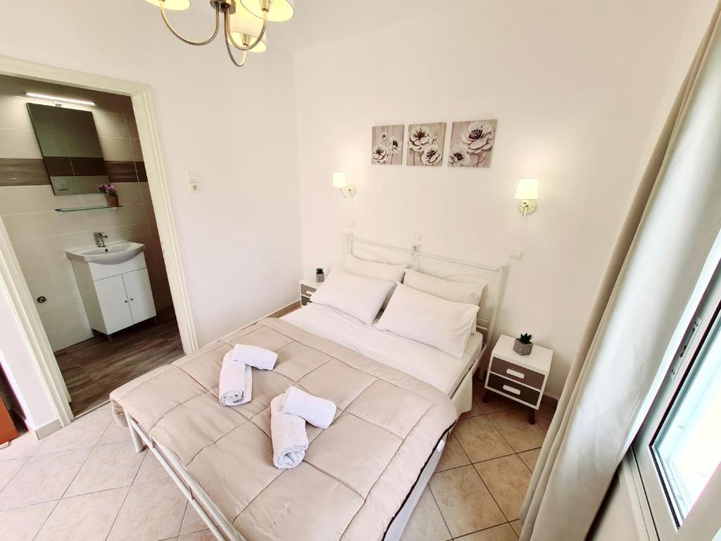 a white bedroom with a bed with towels on it at Avra Rooms in Karpathos Town