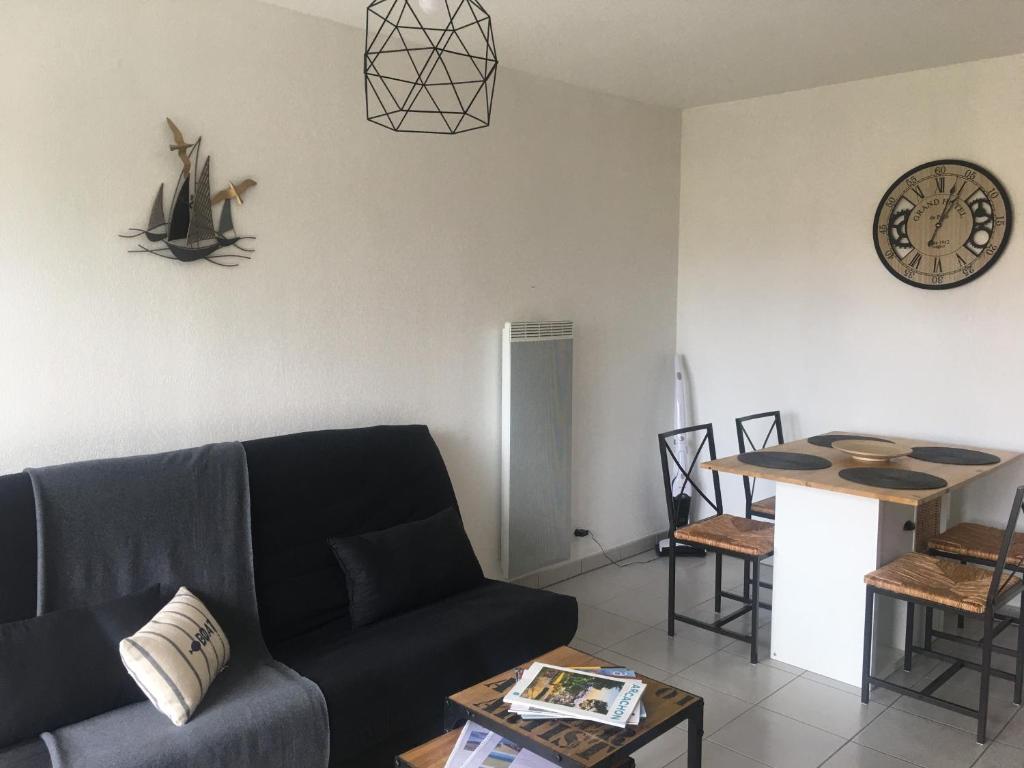 a living room with a couch and a clock on the wall at Colibri Appart&#39; T2 au coeur du Bassin d&#39;Arcachon in Gujan-Mestras