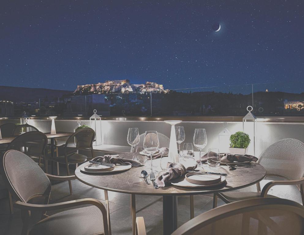 a table with wine glasses on a balcony at night at MiraMe Athens Boutique Hotel-House of Gastronomy in Athens