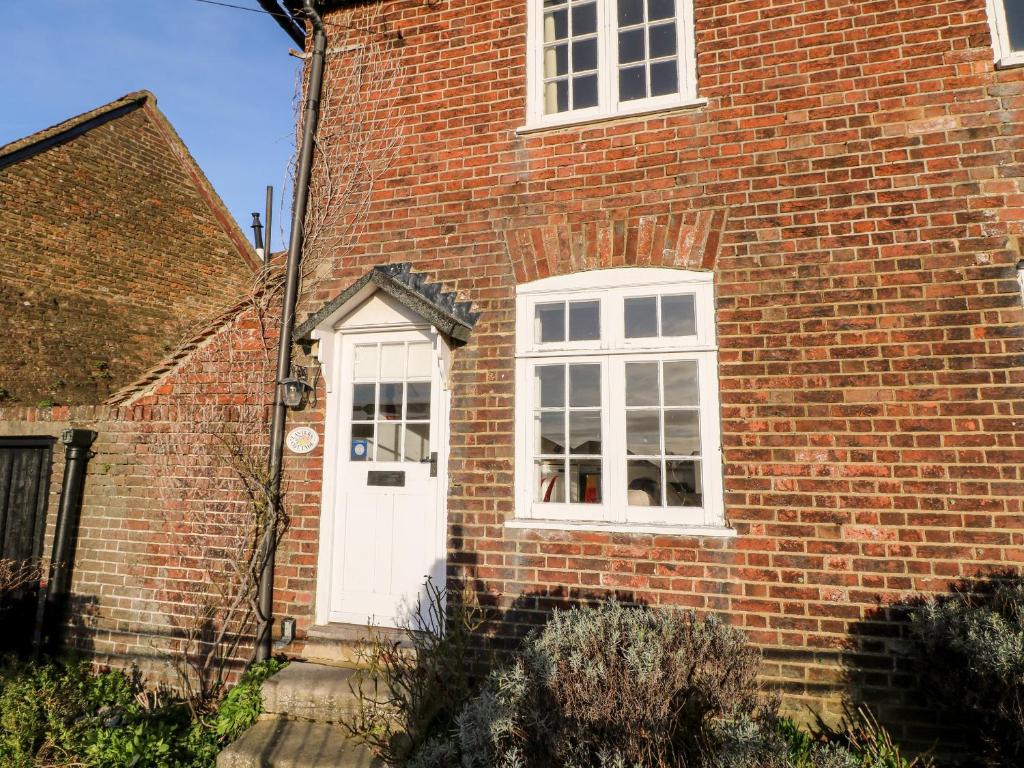 uma casa de tijolos com uma porta branca e janela em Lantern Cottage em Rye