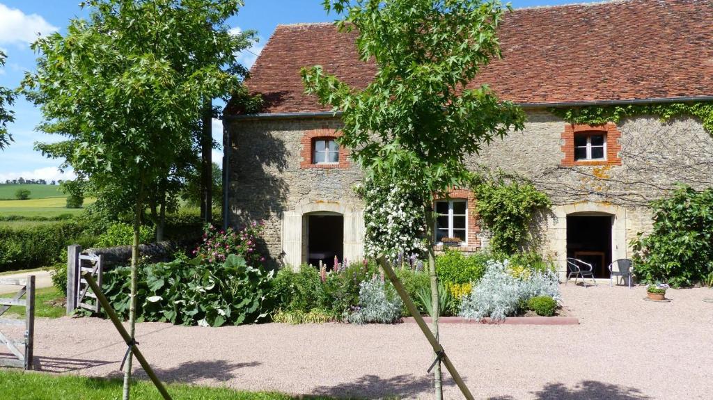 una vecchia casa in pietra con dei fiori davanti di La Colombière a Lurcy-le-Bourg