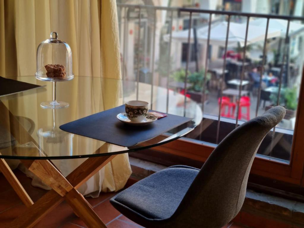 uma mesa de vidro com uma chávena de café e uma cadeira em Suite del Mercante em Mantova