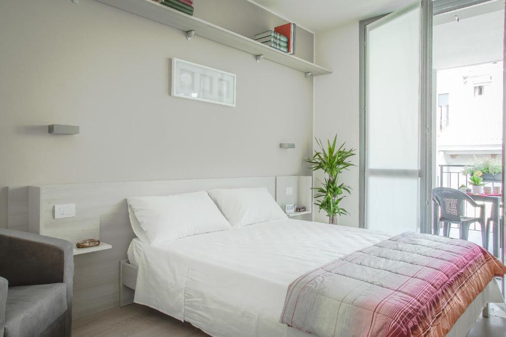 1 dormitorio blanco con 1 cama y 1 silla en Alfa Bicocca Apartments, en Milán