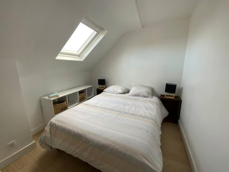 um quarto branco com uma cama e uma janela em Studio du Cairn em Wimereux