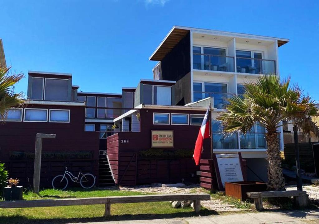 a building with a bench in front of it at Pichilemu Surf Hostal in Pichilemu