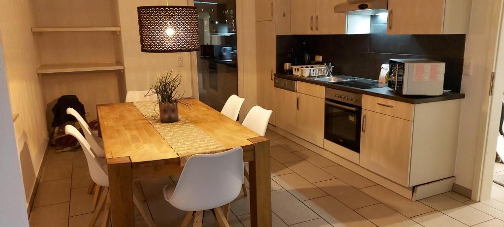 cocina con mesa de madera y sillas blancas en Ferienwohnung KaMa, en Bitburg