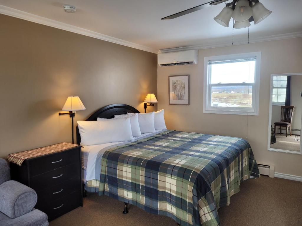 a bedroom with a bed and a chair and a window at CARLETON INN & COTTAGES in Bridgetown