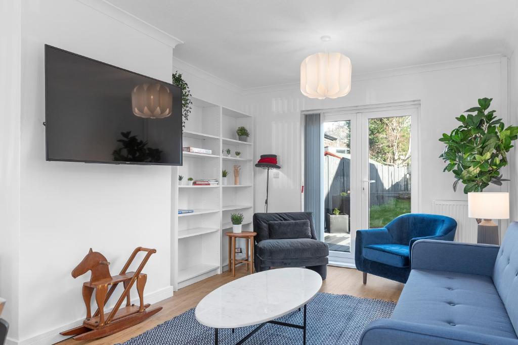 a living room with blue chairs and a tv at MyCityHaven - The Grove. Superb house sleeps 8 in Avonmouth