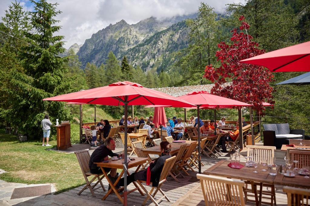 a group of people sitting at tables under red umbrellas at Relais des Merveilles in Belvédère