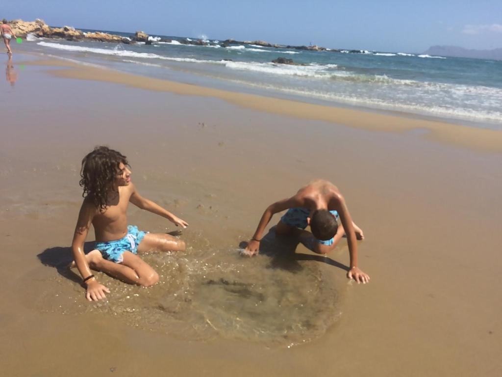dos niños jugando en el agua en la playa en Ouranos Studios, en Kalamaki