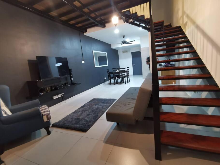 ein Wohnzimmer mit einer Treppe, einem Sofa und einem Tisch in der Unterkunft Lakeview Duplex Apartment Free WiFi and Netflix in Cyberjaya