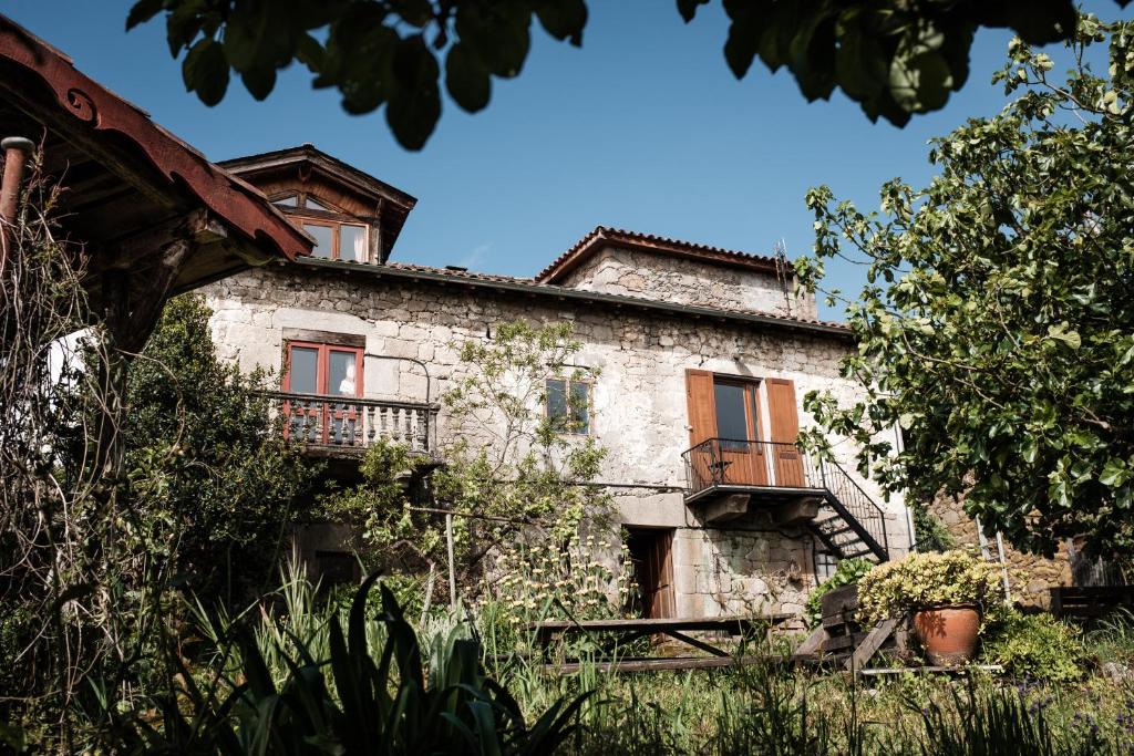 an old stone house with a balcony on the side of it at Torre Tanquián Eco Finca - Ribeira Sacra in Pantón