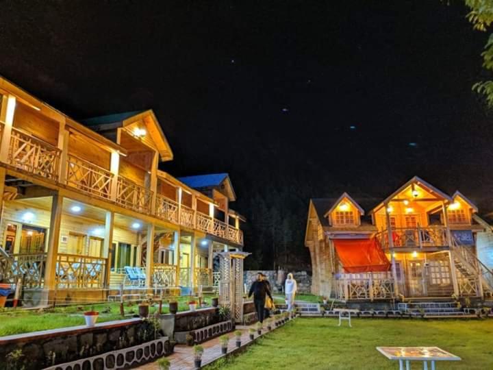 a group of buildings with people standing outside at night at Swiss Wood Cottages Naran in Nārān