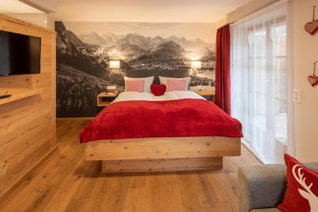 a bedroom with a large bed with a red blanket at Allgäu-Moni in Füssen