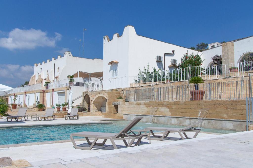 una piscina con due sedie a sdraio di fronte a un edificio di Masseria Bufolaria a Ugento